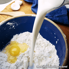 Milk being poured into a bowl with flour and an egg.